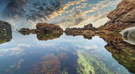Beautiful seascape, ocean views, rocky coast, sunlight on the horizon. Composition of nature. Sunset scenery background. Cloudy sky. Water Reflection. California Seashore.