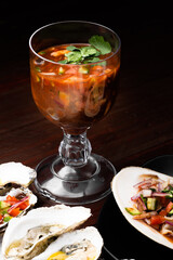 ostiones y almejas frescos con mantequilla y vegetales en cama de sal y mesa de madera elegante 