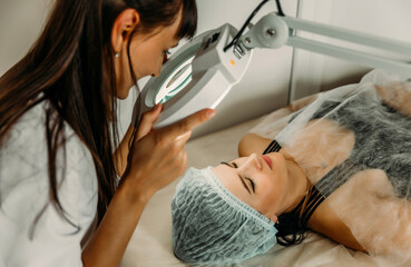 Image of Closeup of Woman in Cosmetic Cabinet under lamp. Faces skin cleaning.