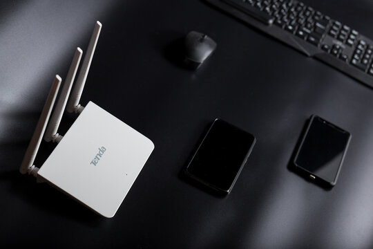 White wifi router Tenda with gadgets on black. Editorial image og brand Tenda.