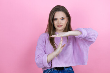 Young pretty woman with long hair standing over isolated pink background Doing time out gesture...