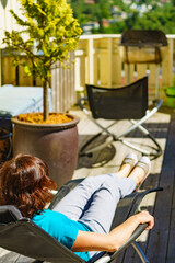 Woman relaxing in chair on veranda.