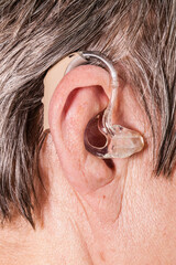 Closeup senior woman using hearing aid