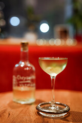 A classic dry martini cocktail in an elegant coupe glass, garnished with grapes. Shot at the bar, wooden table, red background. Photo with shallow depth of field.