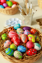 Group of easter eggs painted with handmade and bright color in basket and paintbrush tools blur in the background