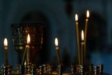 Church candles burn in a candlestick against the backdrop of icons