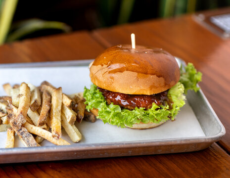 hamburguesas americanas con papas fritas en charolas de metal con mucho queso 
