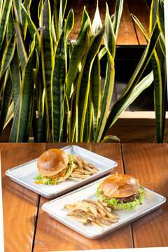 hamburguesas americanas con papas fritas en charolas de metal con mucho queso 
