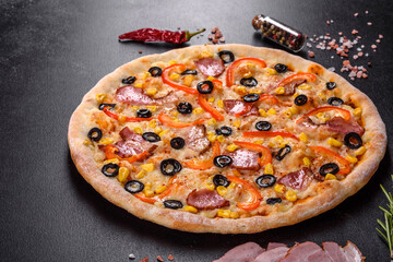 Fresh delicious pizza made in a hearth oven with olives, chili pepper and ham