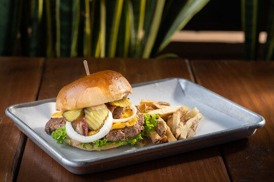 hamburguesas americanas con papas fritas en charolas de metal con mucho queso 
