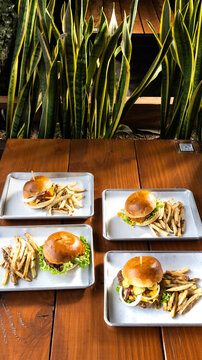 hamburguesas americanas con papas fritas en charolas de metal con mucho queso 
