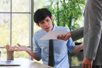A young junior employee feels surprise and does not agree with his boss that abuses him about his work