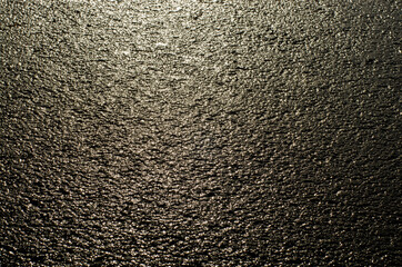 asphalt textured background, the sun is reflected from the wet sidewalk after the rain