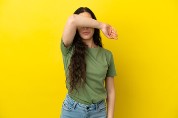Young caucasian woman isolated on yellow background covering eyes by hands