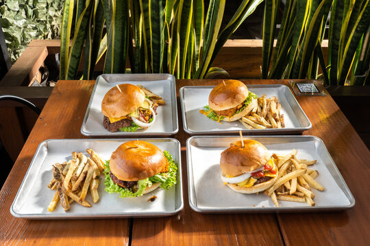 hamburguesas americanas con papas fritas en charolas de metal con mucho queso 
