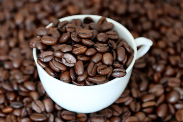 Coffee beans in white cup. Dark and roasted, concept of natural drink