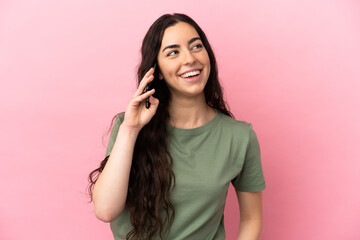 Young caucasian woman isolated on pink background keeping a conversation with the mobile phone with someone