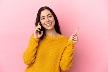 Young caucasian woman using mobile phone isolated on pink background showing and lifting a finger...