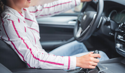 Hands on the steering wheel or gear lever of a car while driving on the road. Transport concept.