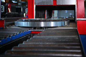 The finished large diameter bearing is coated with oil before packaging and storage. Metal products. Conveyor in the production of bearings. Out of focus. Engine oil.