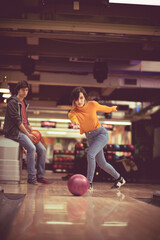 Couple in blowing  alley. Woman throws a bowling ball.