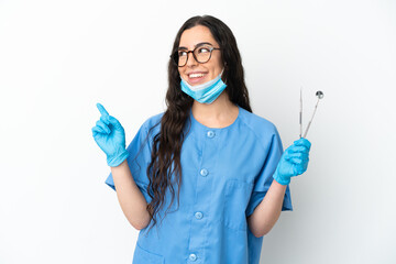 Young woman dentist holding tools isolated on white background pointing up a great idea