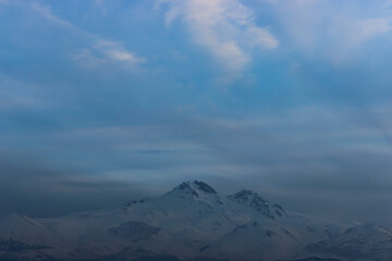 Obraz premium Snowy view of Mount Erciyes in Kayseri, Turkey. Cityscape with mountain and clouds in the evening.
