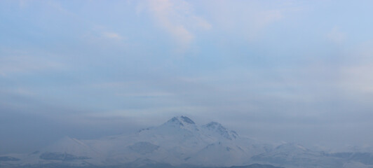 Snowy view of Mount Erciyes in Kayseri, Turkey. Cityscape with mountain and clouds in the evening.