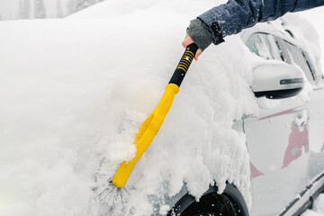 Closeup of car brush in woman hand. Woman wipe snow from a fender of her car.