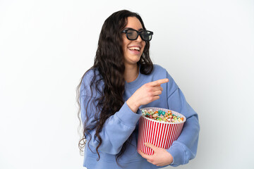 Young caucasian woman isolated on white background with 3d glasses and holding a big bucket of popcorns while pointing front