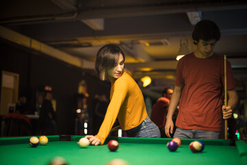 Young couple spending time in billiard room. Billiard game.
