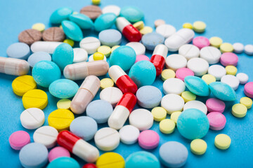 A lot of multicolored pills and capsules on a blue background as a concept of addiction from medicine. Vitamins to keep immunity on a high level.