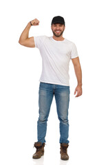 Casual Young Man Is Standing, Flexing Biceps And Smiling