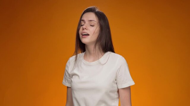 Young sick woman sneezing into elbow against yellow background