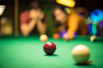 Couple playing a billiard. Focus is on billiards ball.