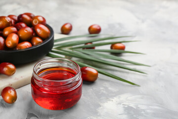 Palm oil in glass jar, tropical leaf and fruits on grey table. Space for text