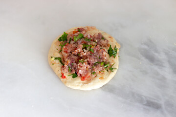 Preparation of homemade pastry, pita, pitta bread with ground meat in the kitchen. Isolated view of pita on marble countertops. Selective focus.