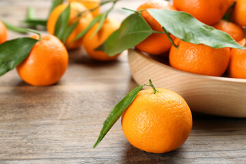 Fresh ripe tangerines with green leaves on wooden table