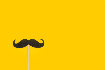 Bigote negro sobre un fondo amarillo. Vista superior. Copy space. Día del padre. Mes de concientización sobre la salud de los hombres.