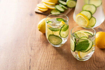 Sassy water or water with cucumber and lemon on wooden table. Copy space