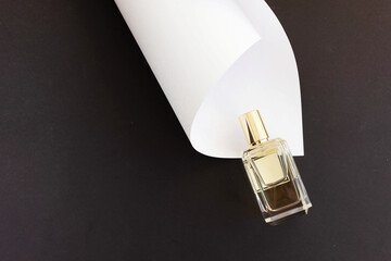 glass perfume bottle on black background with white paper sheet.Classic elegant scent concept. Copy space