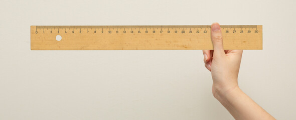 front view, hand holding wooden ruler on isolated background