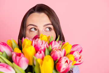 Fototapeta premium Close-up portrait of attractive funny curious girl smelling bunch tulips hiding thinking copy space isolated over pink pastel color background