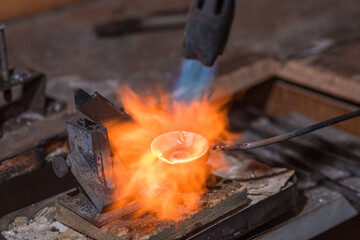 Melting process of precious metal gold behind a jeweler's workbench