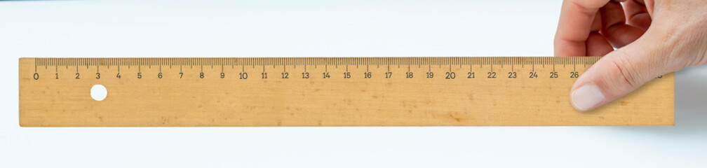 front view, hand holding wooden ruler on isolated background