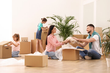 Happy family unpacking moving boxes in new house