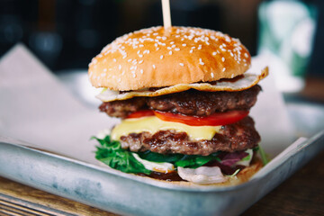 Big burger on restaurant table, close-up, small focus depth, toned