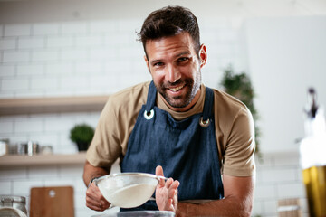 Obraz na płótnie Canvas Happy man baking in the kitchen. Man making fresh pasta at home