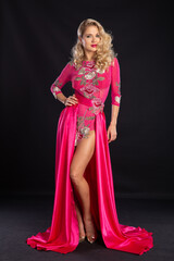 Obraz premium Beautiful blonde in a pink sexy dress on a black background.