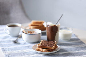 Delicious breakfast with toasts and chocolate paste on table